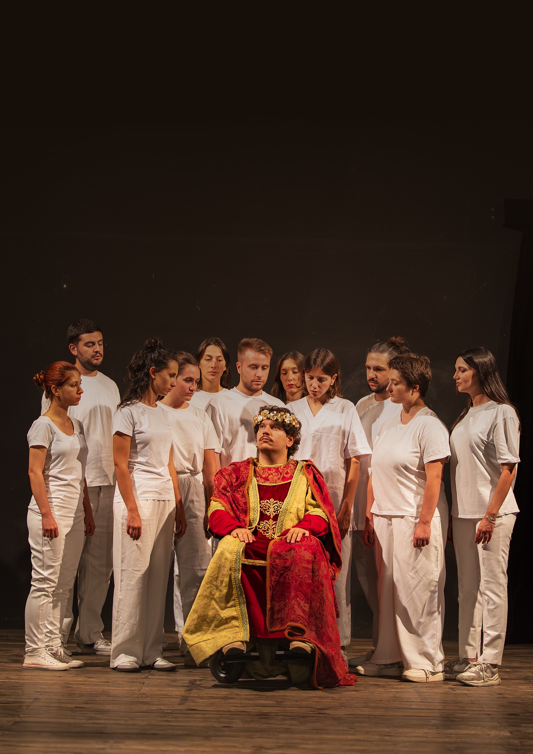 Il cast di Enrico IV in scena, con Enrico incoronato al centro circondato dai consiglieri.